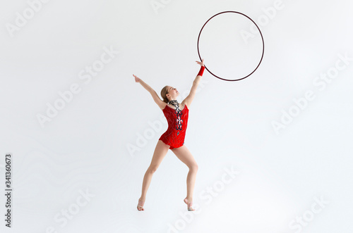 Full length portrait of gymnast in leotard suit making exercises with hoop, white background © Prostock-studio