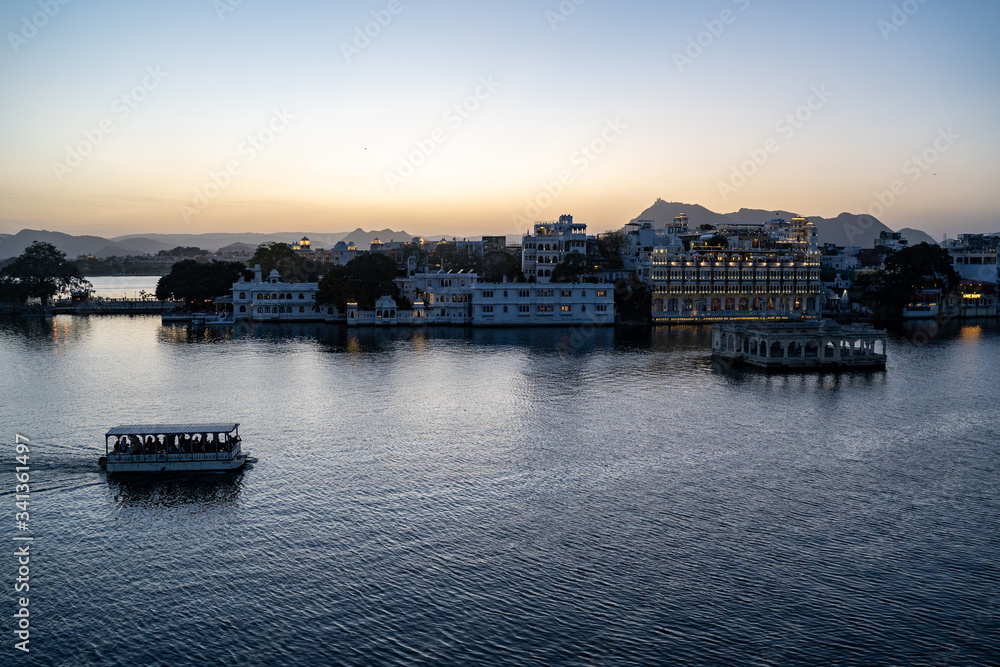 Udaipur, Rajasthan India - Sunset evening view of Lake Pichola as a passenger ferry boat sails by