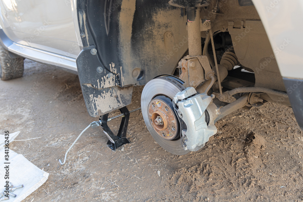 View of the front axle of a car without a wheel. The car is on the jack