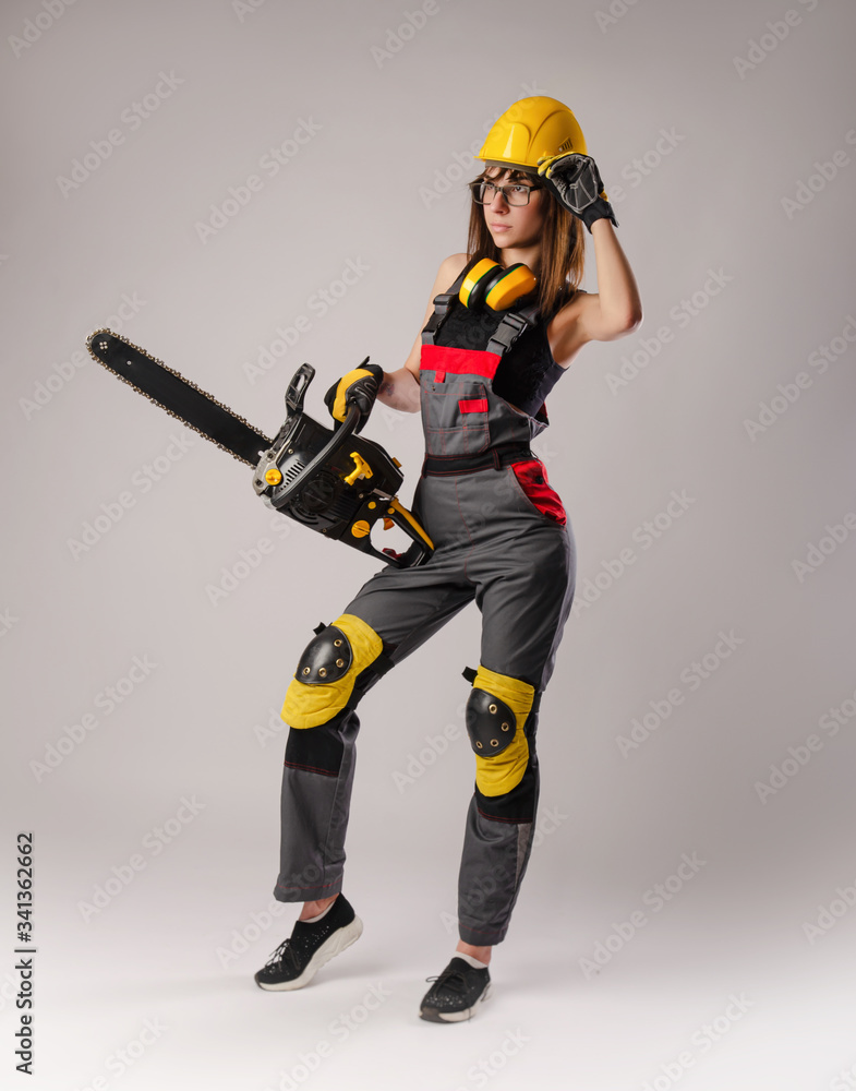 Girl in overalls with a chainsaw in white background Girl in overalls with a chainsaw in white background