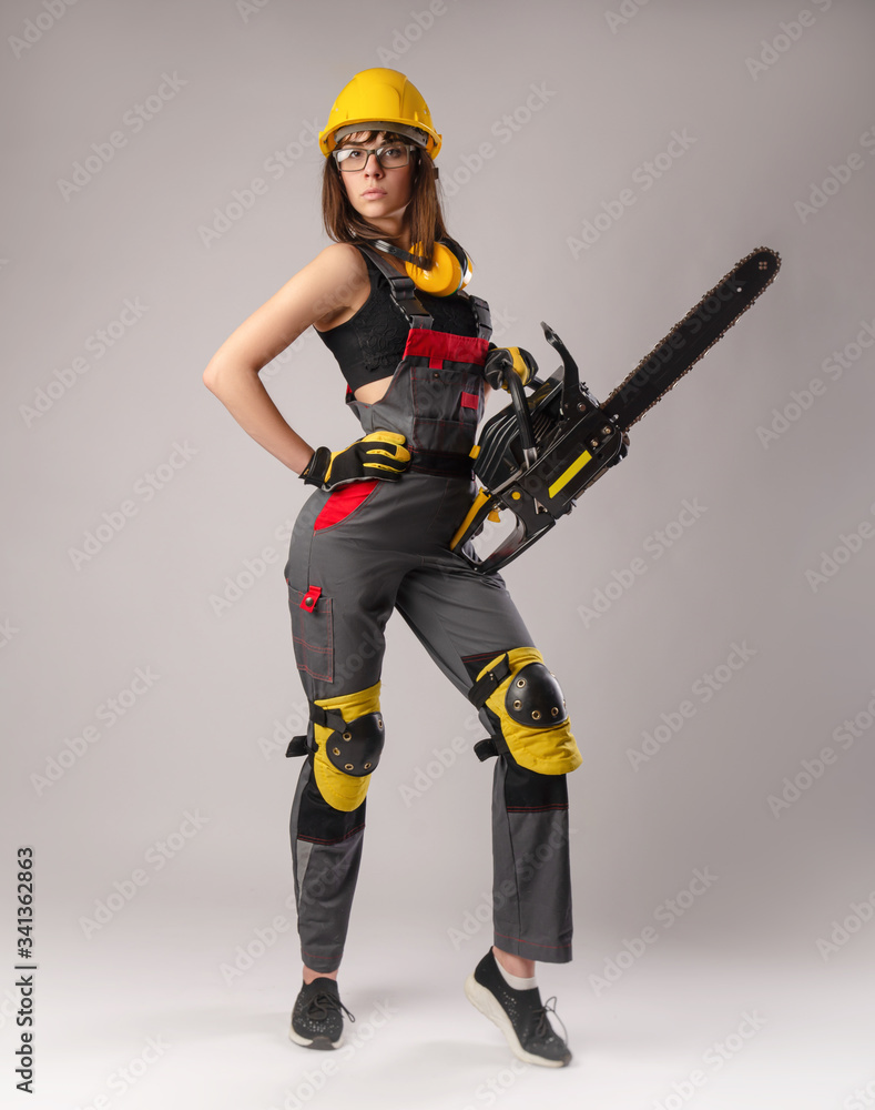 Girl in overalls with a chainsaw in white background Girl in overalls with a chainsaw in white background