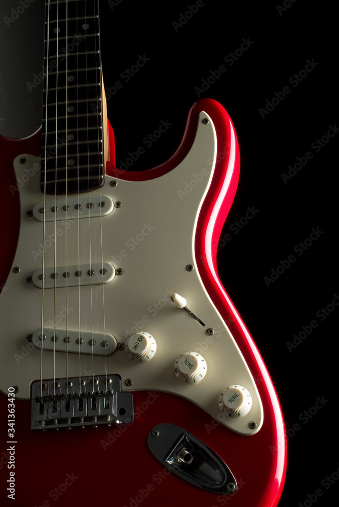 A vibrant red electric guitar over a black background.