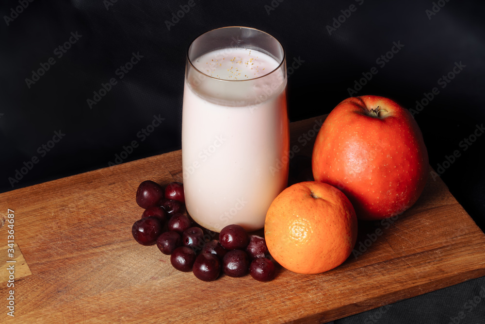 Apple cherry citrus smoothie on a wooden board with fruits on a black background Apple cherry citrus smoothie on a wooden board with fruits on a black background