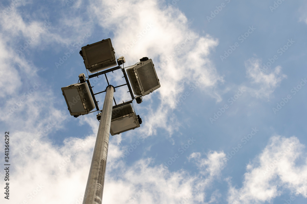 Searchlights on a pole against a blue sky with clouds. Searchlights on a pole against a blue sky with clouds.