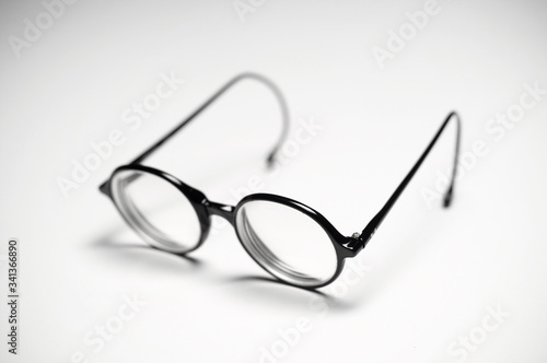 A single vintage pair of round reading glasses over a white tabletop. 