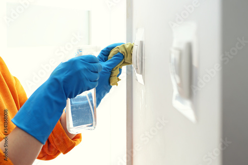 Contact disinfection, disinfection of switches. Prevention and prevention of infection. The woman disinfects the light switches. photo