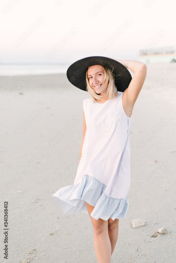 Girl in a hat walks on the beach