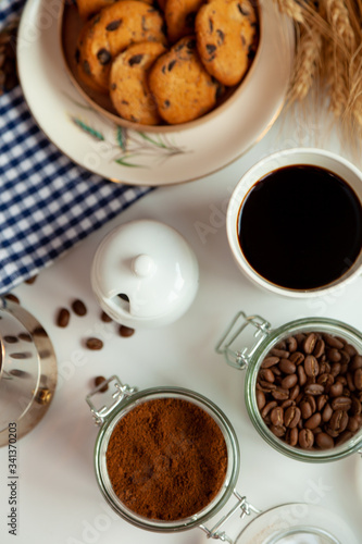 White cup of coffee and homemade round cookies with chocolate chips. Breakfast is on the table. Food at home. Still life. Coffee and coffee beans. An invigorating drink. Top view, flat lay.