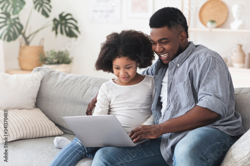 Happy African Father And His Little Daughter Using Laptop At Home