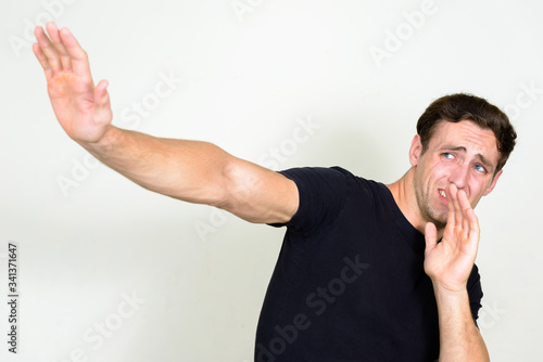 Portrait of stressed young man looking scared with arms raised