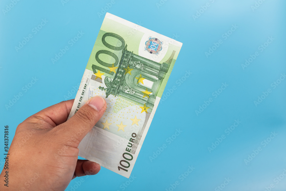 100 Euro note on hand isolated on blue background 100 Euro note on hand isolated on blue background