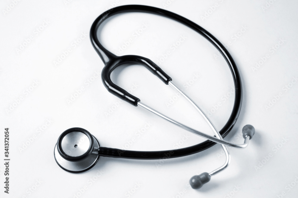A single black stethoscope over a white tabletop surface. A single black stethoscope over a white tabletop surface.