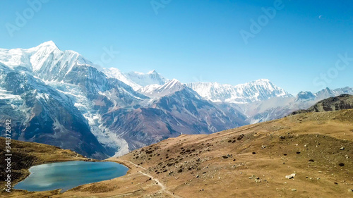 Ice lake, as part of the Annapurna Circuit Trek detour, Himalayas, Nepal. Annapurna chain in the back, covered with snow. Clear weather, dry grass, snowy peaks. Freedom, solitude, chill and relaxation photo