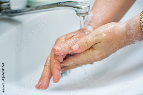Woman washing hands with soap under the faucet with water. Washing hands for daily personal care against Coronavirus pandemic.