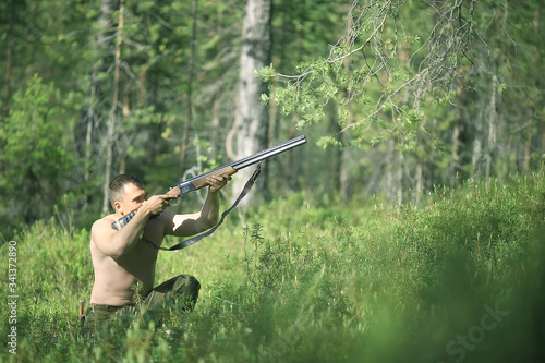 man goes hunting forest summer / landscape in the forest, huntsman with a hunting rifle hunts