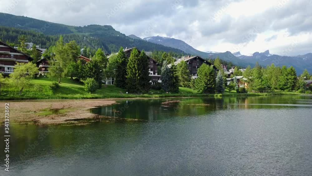 Fly over lake with beautiful chalets in rural switzerland in the mountains Fly over lake with beautiful chalets in rural switzerland in the mountains
