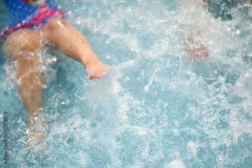 Kid's leg splashing water in the pool, summer holiday