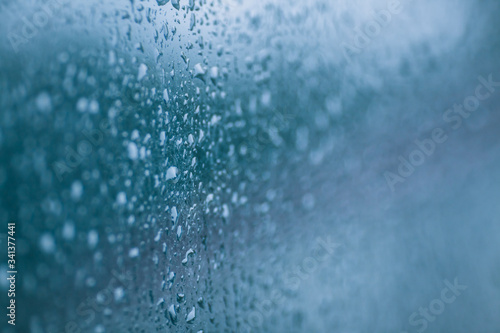 Drops on the glass. Abstract blurred background with wet surface, raindrops on the window. © Simon
