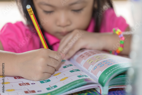 Little asian kid at home doing homework