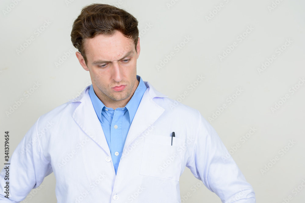 Portrait of stressed young man doctor thinking and looking down Portrait of stressed young man doctor thinking and looking down