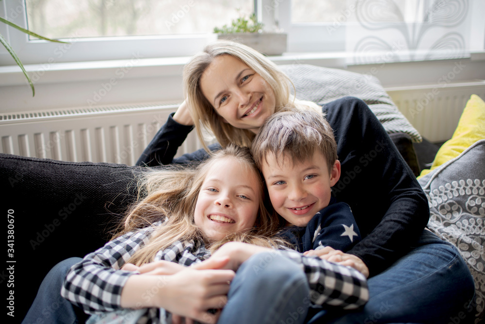 Portrait of happy mother with kids relaxing on couch at home Portrait of happy mother with kids relaxing on couch at home