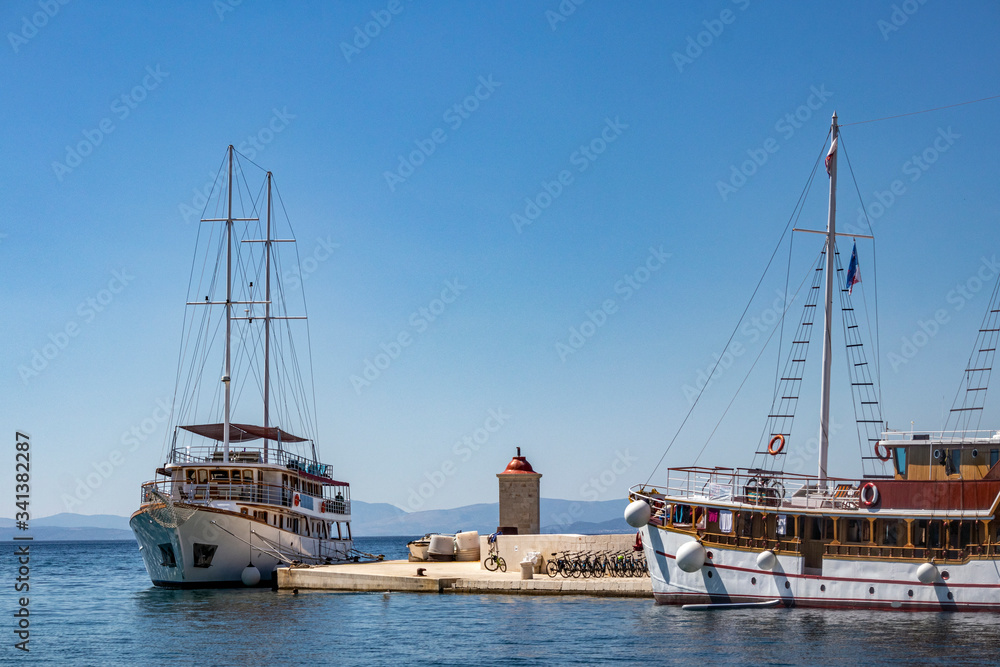 Port and pier of village Postira on island Brac in Croatia with tourist and fishing boats and lighthouse