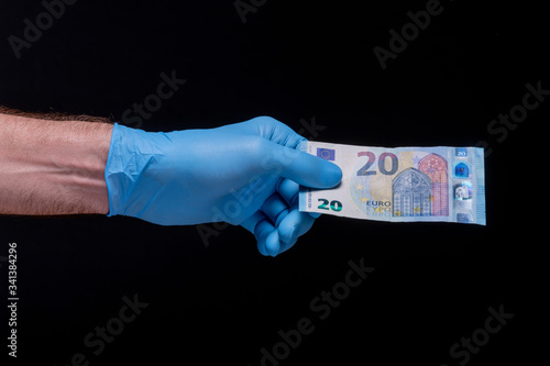 Hand, with a latex glove, holding a euro bill