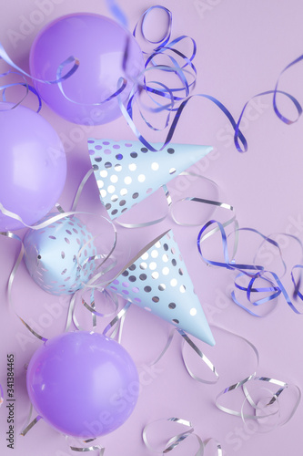 Blue caps, purple balls and silver serpentine on a purple paper background. Holiday background.