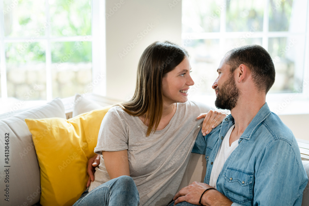 Affectionate young couple in love smiling at each other on couch at home Affectionate young couple in love smiling at each other on couch at home