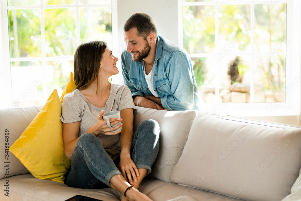 Affectionate couple in love smiling at each other at home on couch Affectionate couple in love smiling at each other at home on couch