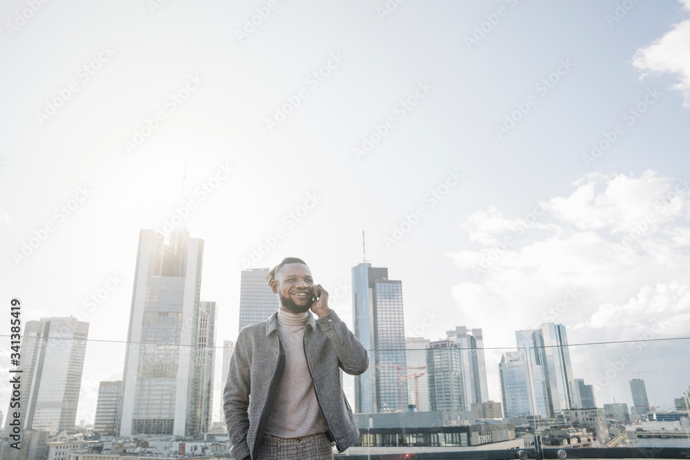 Smiling man on the phone on observation terrace with skycraper view, Frankfurt, Germany Smiling man on the phone on observation terrace with skycraper view, Frankfurt, Germany