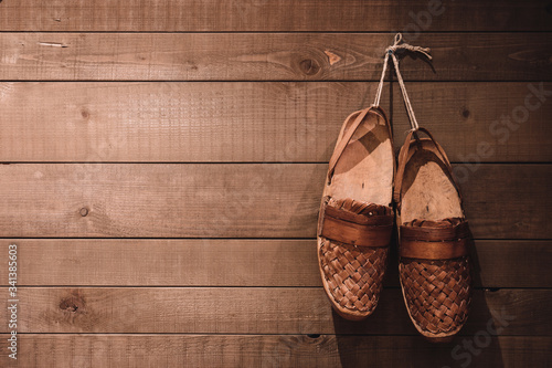 Old shepherds shoes, hanging on a wooden background.