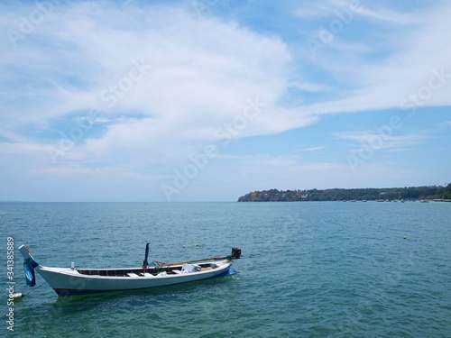 Blue sea and white boat. Panoramic view of azure water surface, beautiful sky with clouds, green cape in a distance, horizon. Conceptual picture of seascape. Panorama of nature. Idea for design. 