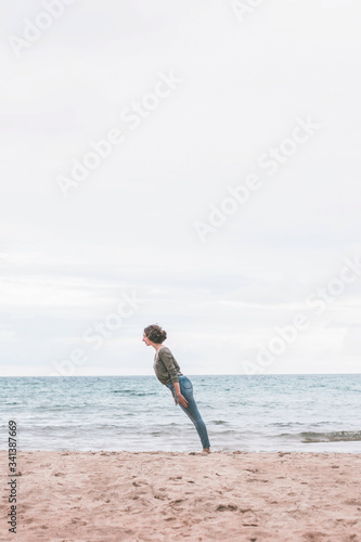 Young woman standing on the beach, tilted photo