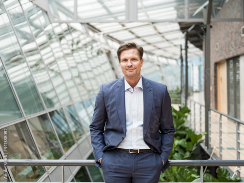 Wallpaper Mural Confident businessman leaning on railing with hands i  pockets Torontodigital.ca