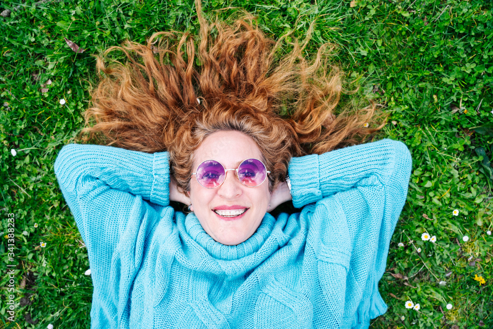Portrait of happy redheaded mature woman lying on grass Portrait of happy redheaded mature woman lying on grass