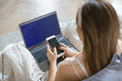 Woman with laptop and smartphone at home.