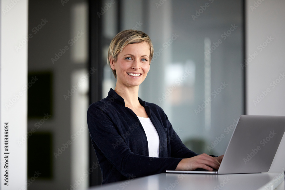 Portrait of smiling businesswoman using laptop in office Portrait of smiling businesswoman using laptop in office