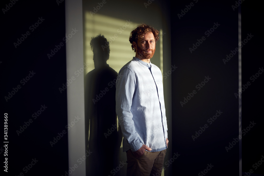 Portrait of a casual businessman standing at a wall