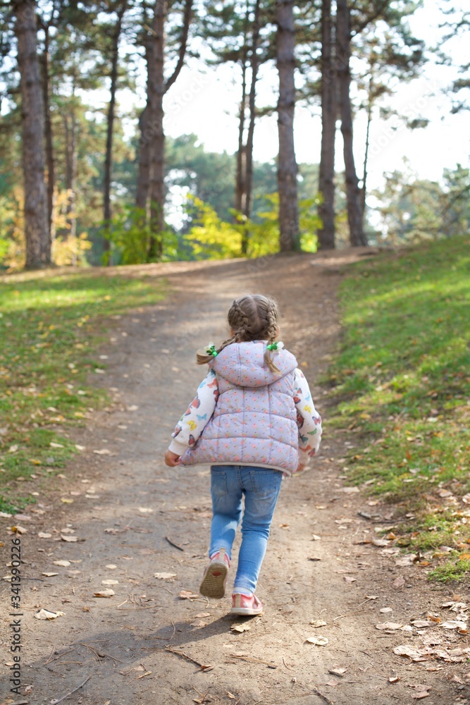A little girl runs along a forest path in an autumn city Park. Weekends are for walking in the fresh air. A little girl runs along a forest path in an autumn city Park. Weekends are for walking in the fresh air.
