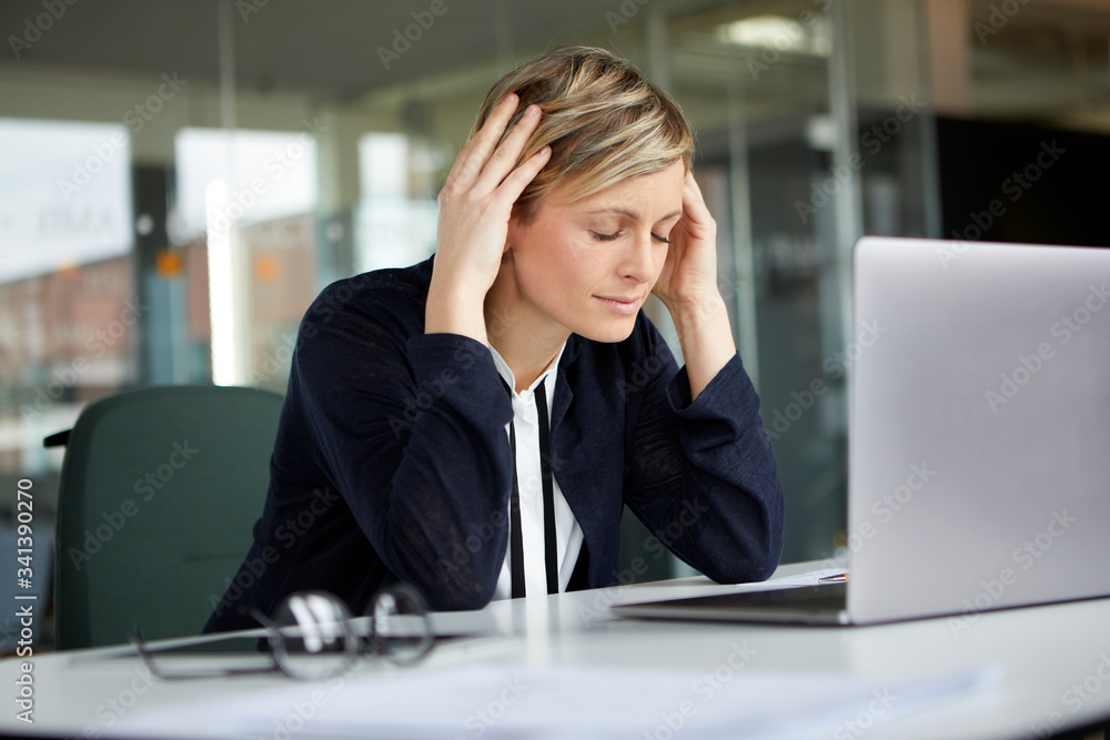 Businesswoman in office with head in hands and closed eyes Businesswoman in office with head in hands and closed eyes