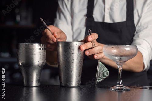 Process of mixing ingredients in cocktail mixer with stirring stick. Cold drink preparation.