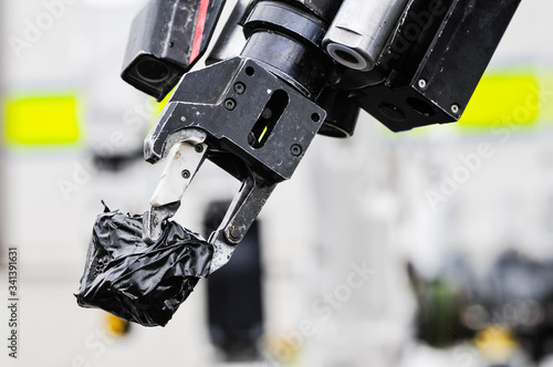 Pincer grip of an army bomb disposal robot holds a suspect object wrapped in tape photo