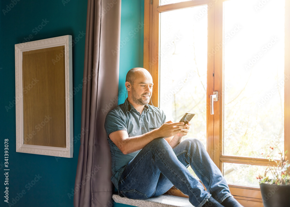 Man sitting at the window holding a mobile phone in his hands