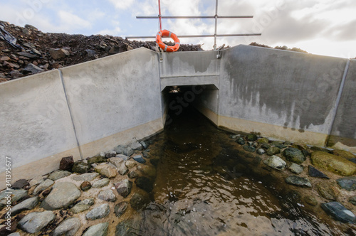 Obraz na plátne Concrete culvert diverting a small stream underneath a newly constructed road