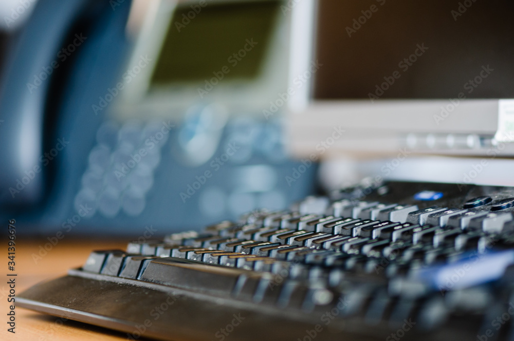 Computer keyboard on an office desk with telephone and monitor