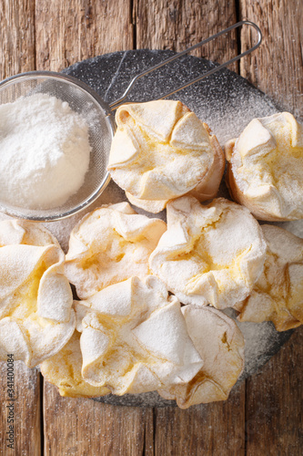 Dietary Italian Soffioni cupcake stuffed with ricotta cheese sprinkled with powdered sugar closeup on a slate board. Vertical top view
 photo