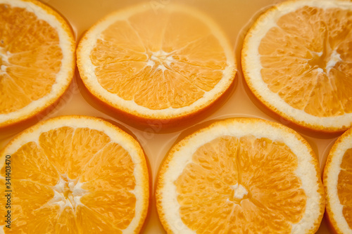 Round fresh orange wet slices, summer yellow background.