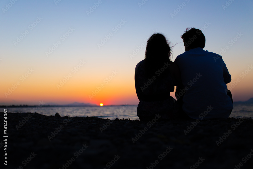 Silhouette of a couple sitting during a sunset Silhouette of a couple sitting during a sunset