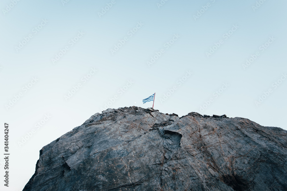 Fototapeta premium Greek flag on a mountain with a blue sky